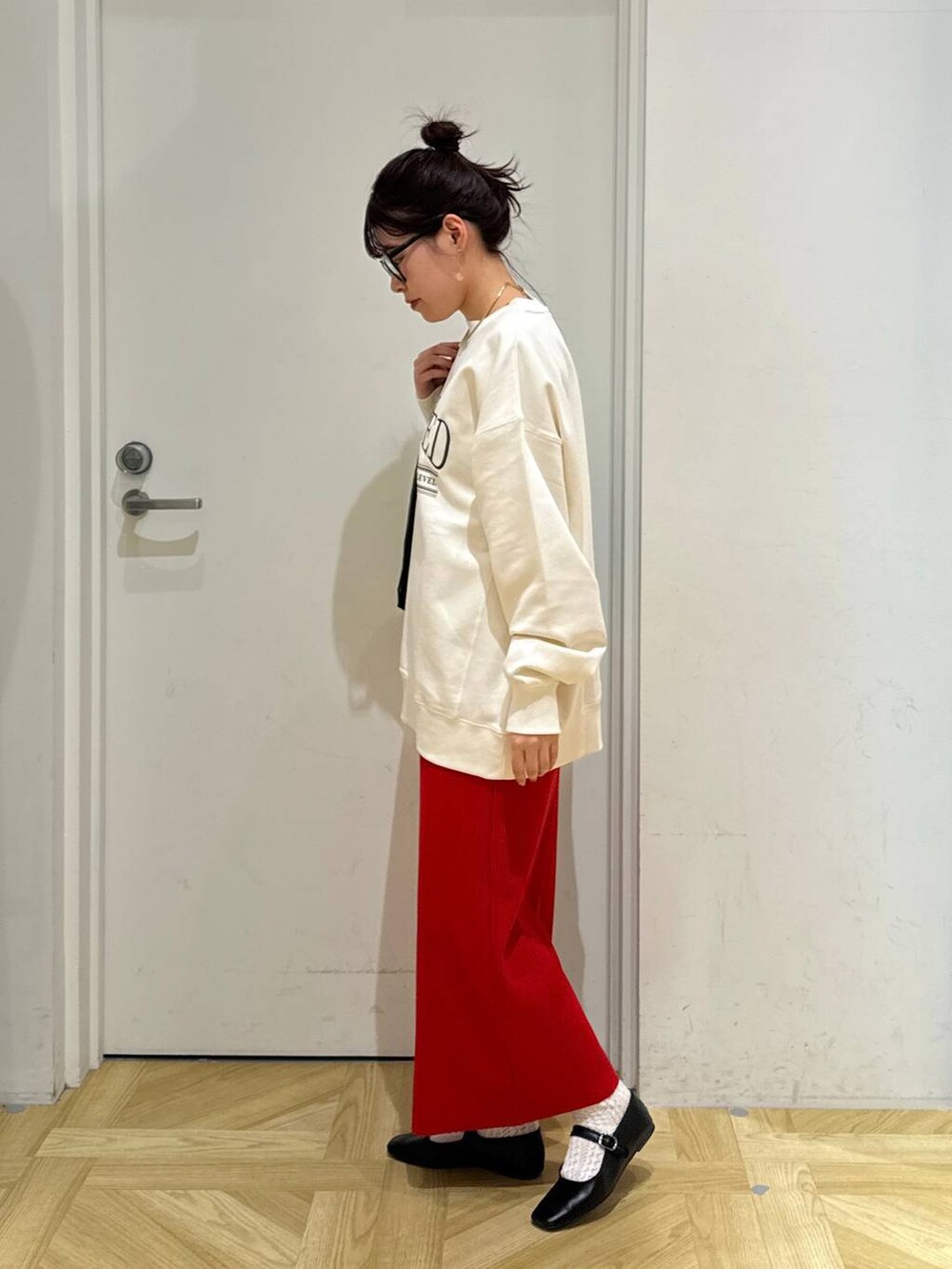 レッド系のスカート、ホワイト系のスウェット、ブラック系のバレエシューズを着用したレディースの春コーディネートの3枚目の写真