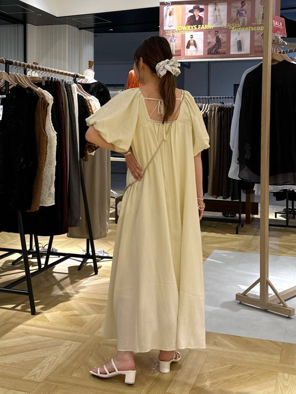 ゴールド系のショルダーバッグ、ホワイト系のサンダル、ホワイト系のワンピースを着用したレディースの夏コーディネートの5枚目の写真