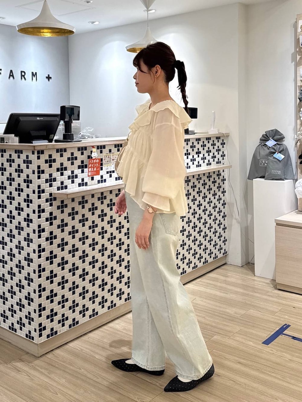 ブラック系のパンプス、ブルー系のデニムパンツ、ベージュ系のショルダーバッグを着用したレディースの春コーディネートの2枚目の写真