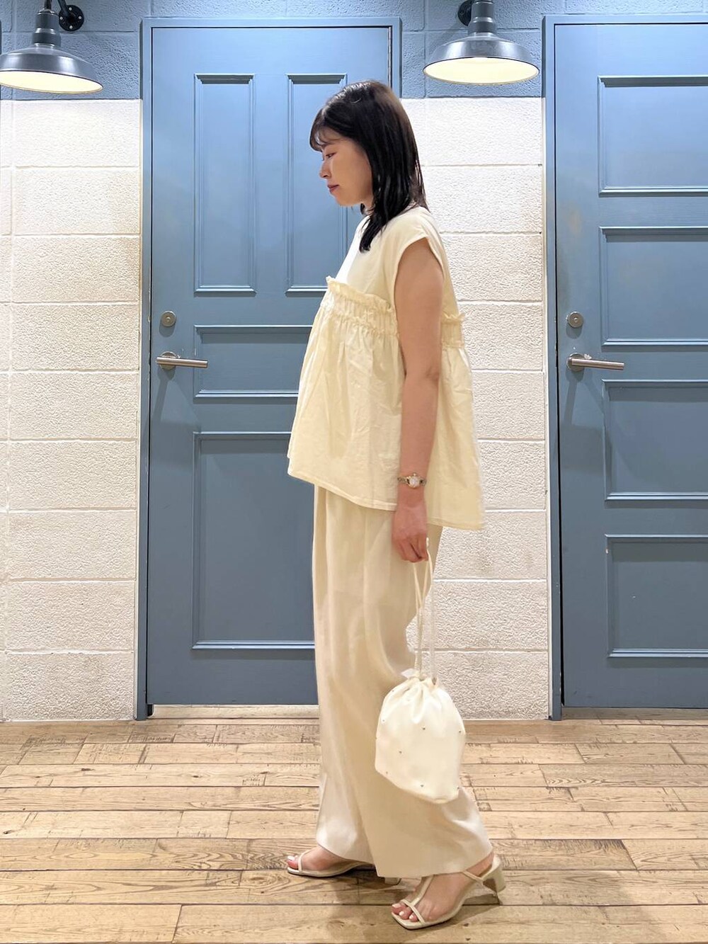 ホワイト系のショルダーバッグ、ホワイト系のスラックス、ホワイト系のサンダルを着用したレディースの夏コーディネートの2枚目の写真