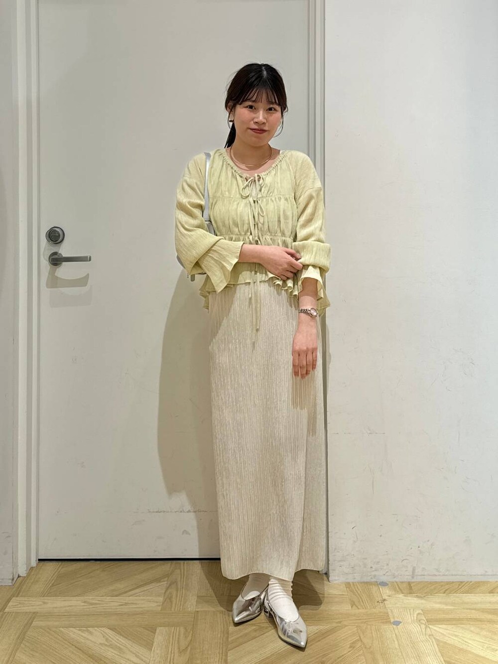 シルバー系のトートバッグ、シルバー系のパンプス、ホワイト系のスカートを着用したレディースの春コーディネートの3枚目の写真