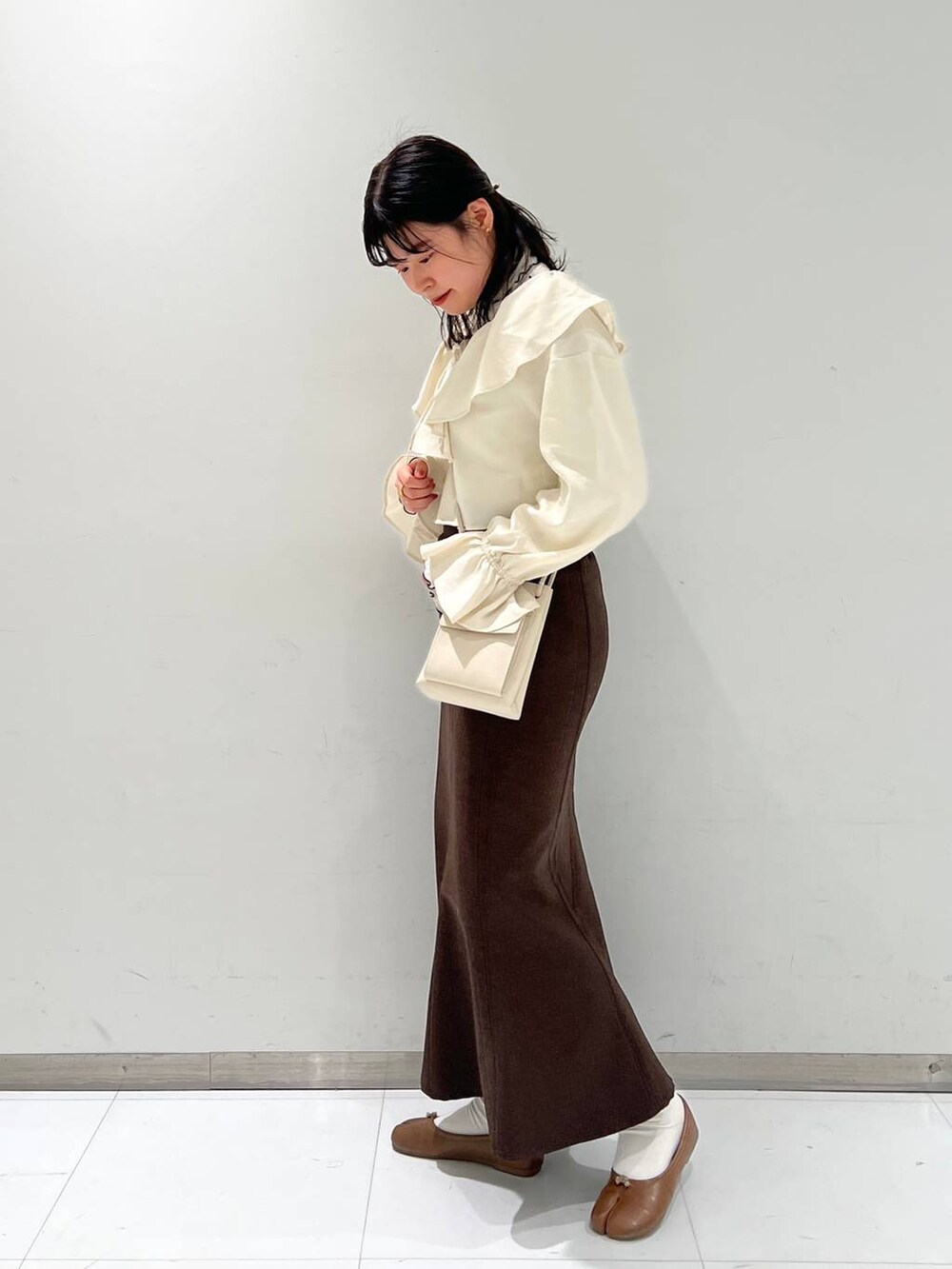 ホワイト系のショルダーバッグ、その他のTシャツ/カットソー、ブラウン系のスカートを着用したレディースの冬コーディネートの2枚目の写真