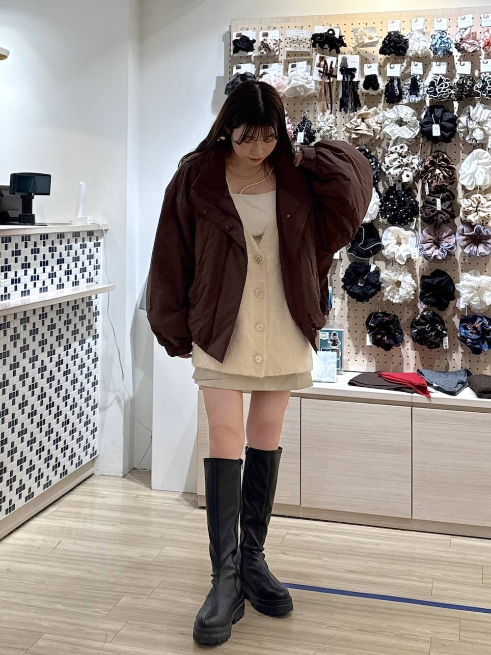 ブラウン系のその他アウター、ホワイト系のスカート、ブラック系のブーツを着用したレディースの秋コーディネートの3枚目の写真