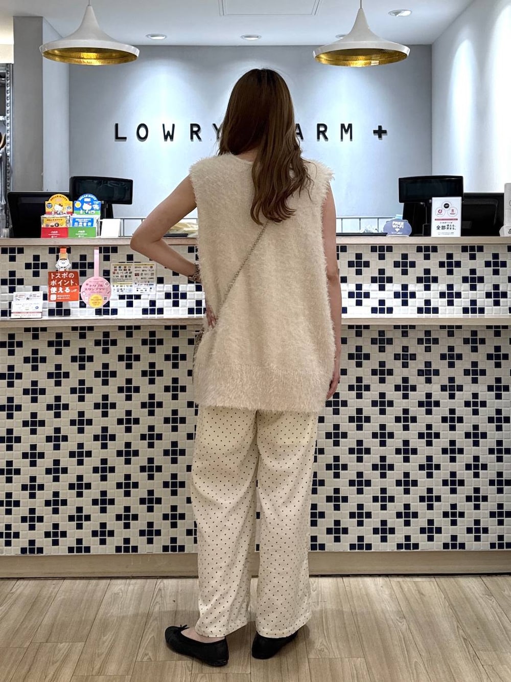 ゴールド系のショルダーバッグ、ホワイト系のベスト、ホワイト系のその他パンツを着用したレディースの秋コーディネートの4枚目の写真