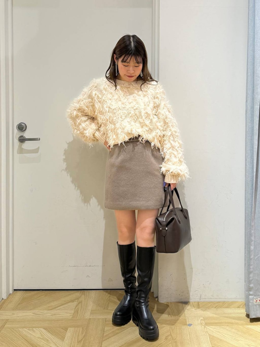 ブラウン系のその他アウター、ブラック系のブーツ、ブラウン系のショルダーバッグを着用したレディースの冬コーディネートの7枚目の写真