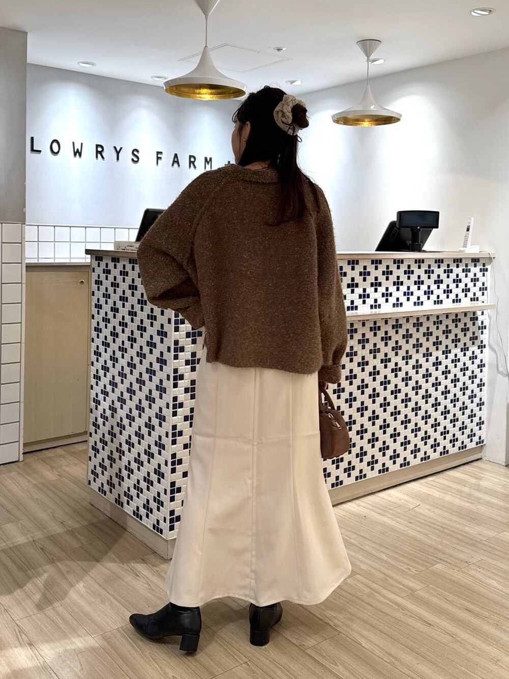 ホワイト系のスカート、ブラウン系のボストンバッグ、ブラウン系のブルゾンを着用したレディースの秋コーディネートの5枚目の写真