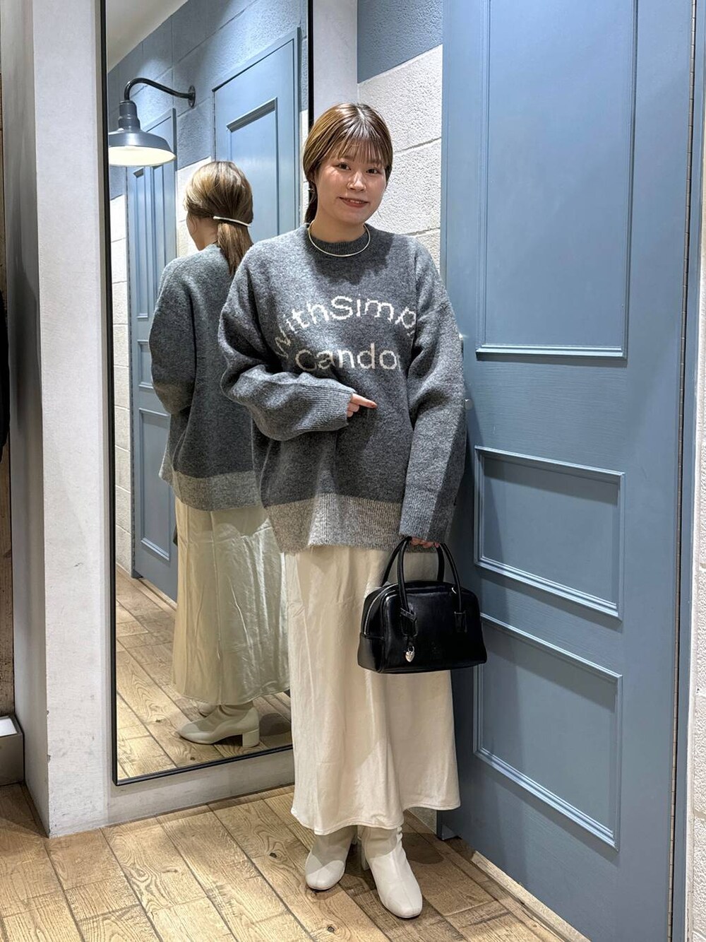 ブラウン系のチェスターコート、ホワイト系のブーツ、ブラック系のボストンバッグを着用したレディースの秋コーディネートの5枚目の写真