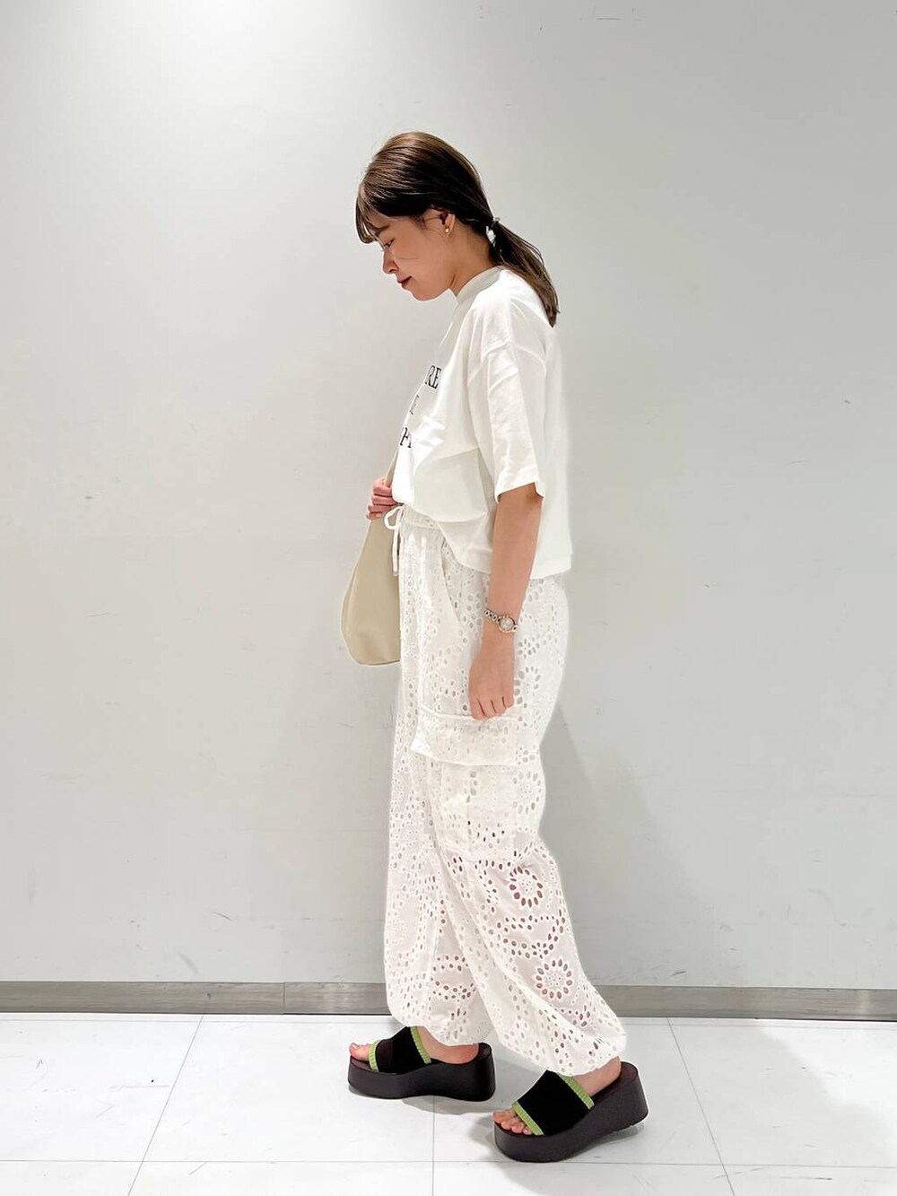 ブラウン系のサンダル、ホワイト系のカーゴパンツ、シルバー系のショルダーバッグを着用したレディースの夏コーディネートの2枚目の写真