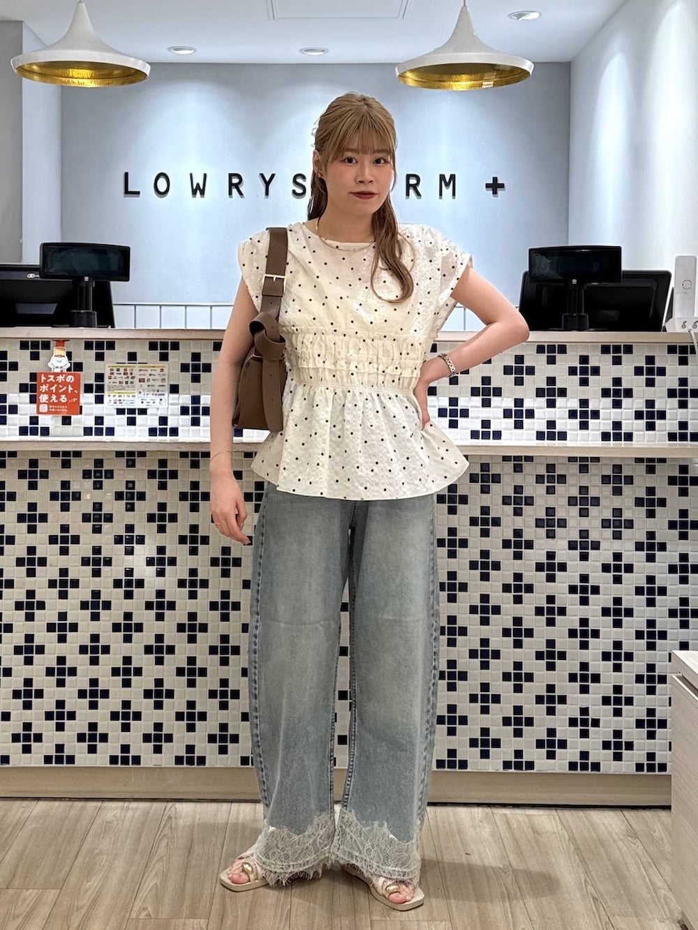 ブルー系のデニムパンツ、ホワイト系のサンダル、ブラウン系のショルダーバッグを着用したレディースの夏コーディネートの2枚目の写真