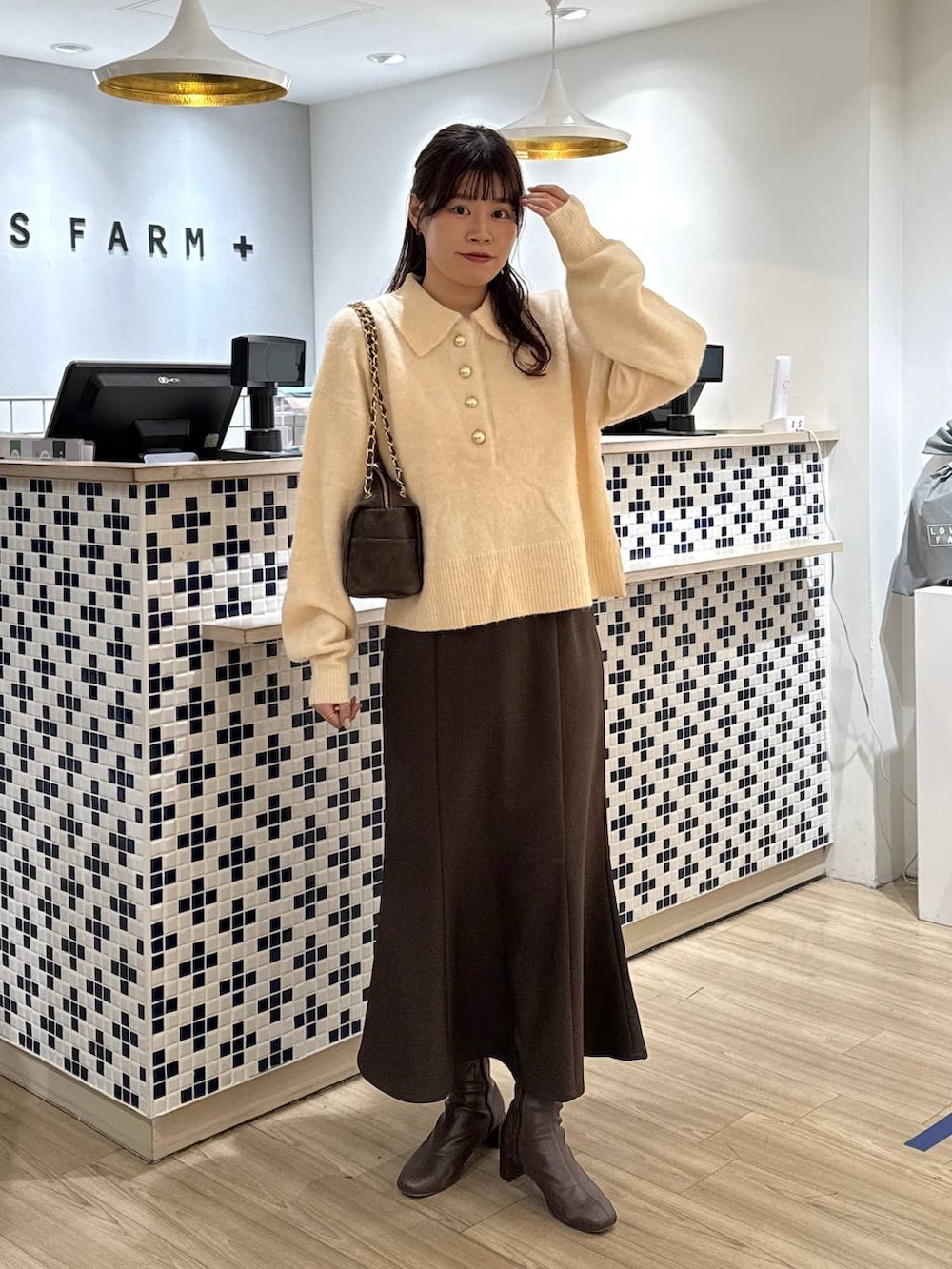 ブラウン系のスカート、ブラウン系のブーツ、ホワイト系のニット/セーターを着用したレディースの冬コーディネートの3枚目の写真