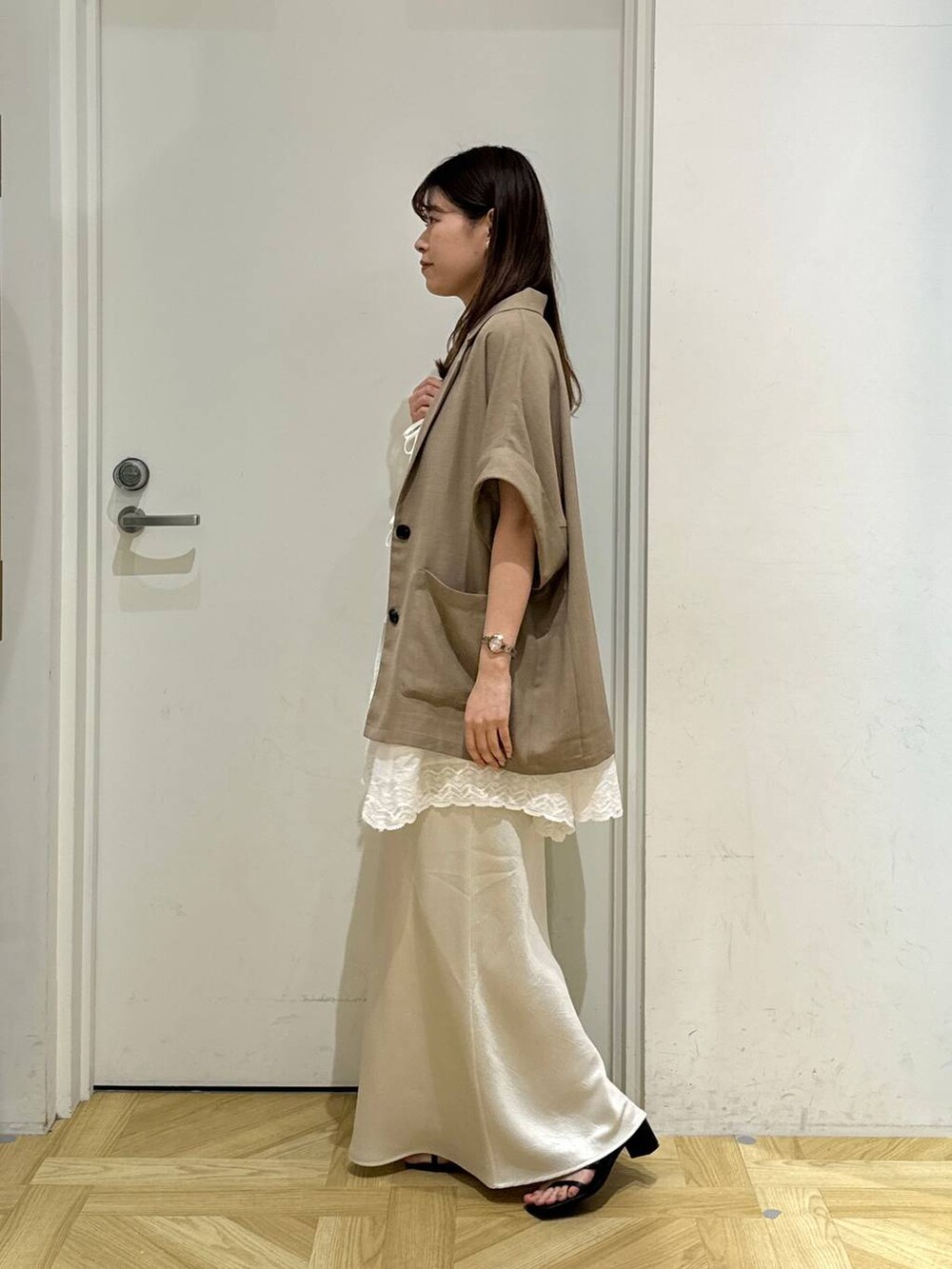 ホワイト系のスカート、ホワイト系のキャミソール、ブラック系のサンダルを着用したレディースの春コーディネートの3枚目の写真