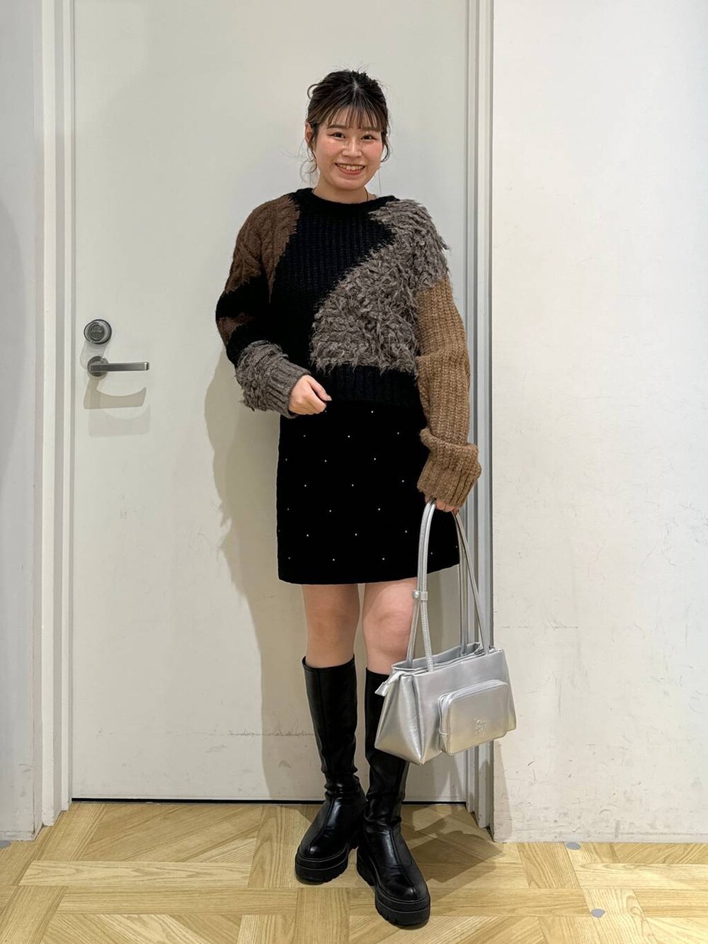 ブラック系のブーツ、シルバー系のショルダーバッグ、ブラック系のニット/セーターを着用したレディースの秋コーディネートの2枚目の写真