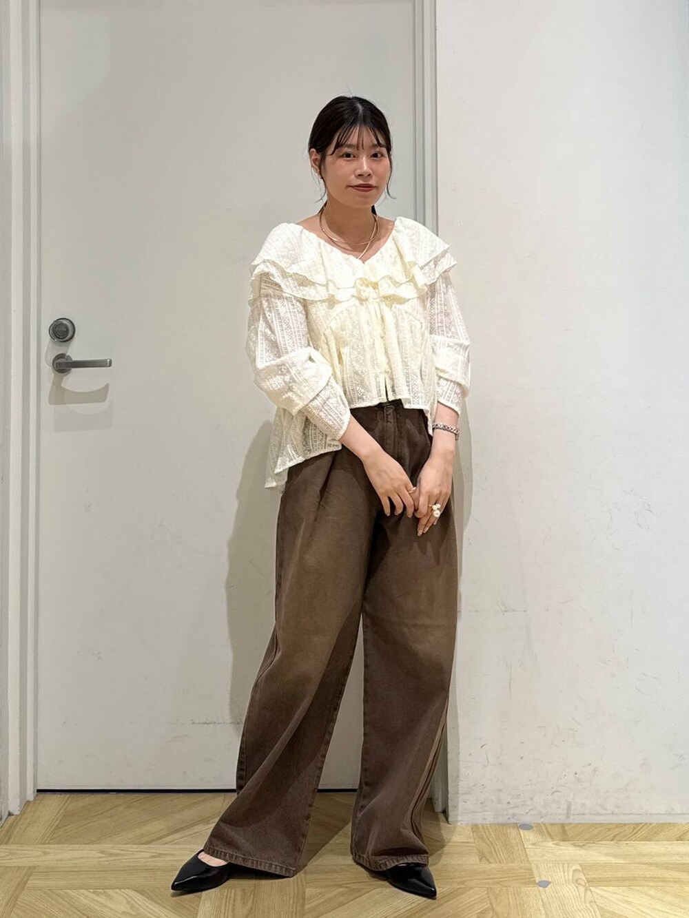 ブラウン系のデニムパンツ、ブラック系のパンプス、ホワイト系のシャツ/ブラウスを着用したレディースの夏コーディネートの4枚目の写真