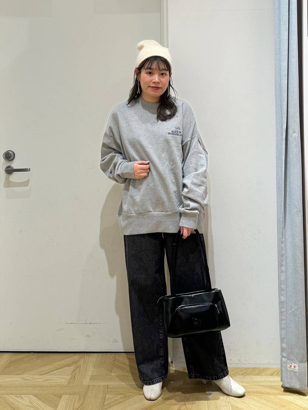 ブラック系のショルダーバッグ、ホワイト系のブーツ、グレー系のスウェットを着用したレディースの秋コーディネートの2枚目の写真