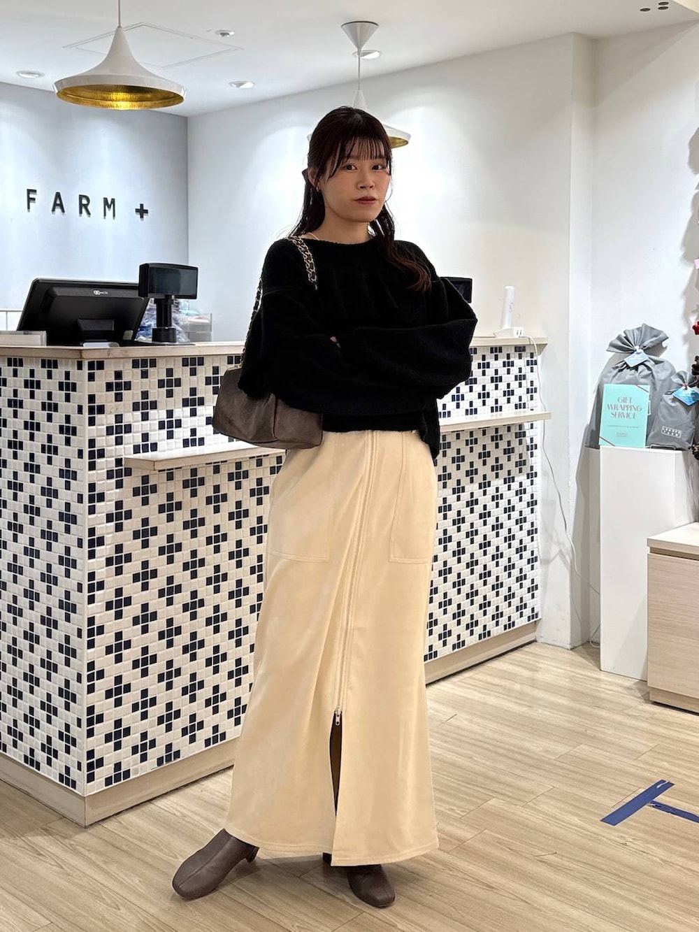 ホワイト系のスカート、ブラウン系のブーツ、ブラウン系のショルダーバッグを着用したレディースの冬コーディネートの3枚目の写真