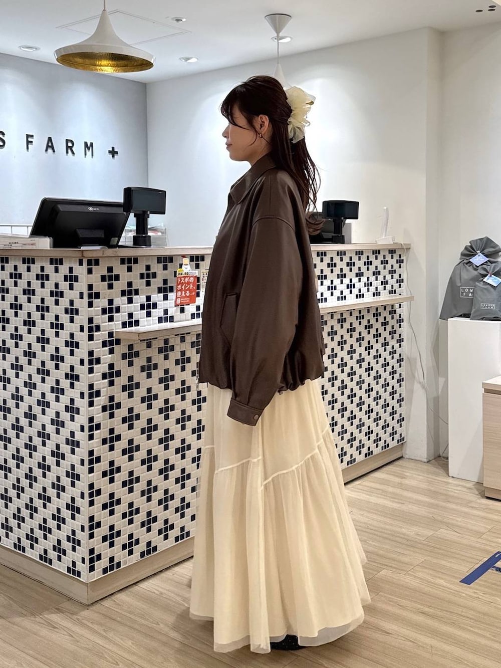 ブラック系のパンプス、ベージュ系のショルダーバッグ、ホワイト系のブルゾンを着用したレディースの春コーディネートの3枚目の写真