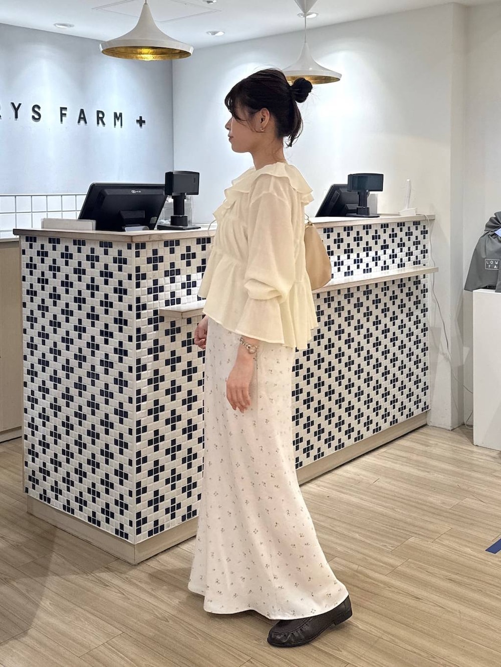 ホワイト系のスカート、ベージュ系のショルダーバッグ、ブラウン系のローファーを着用したレディースの春コーディネートの2枚目の写真