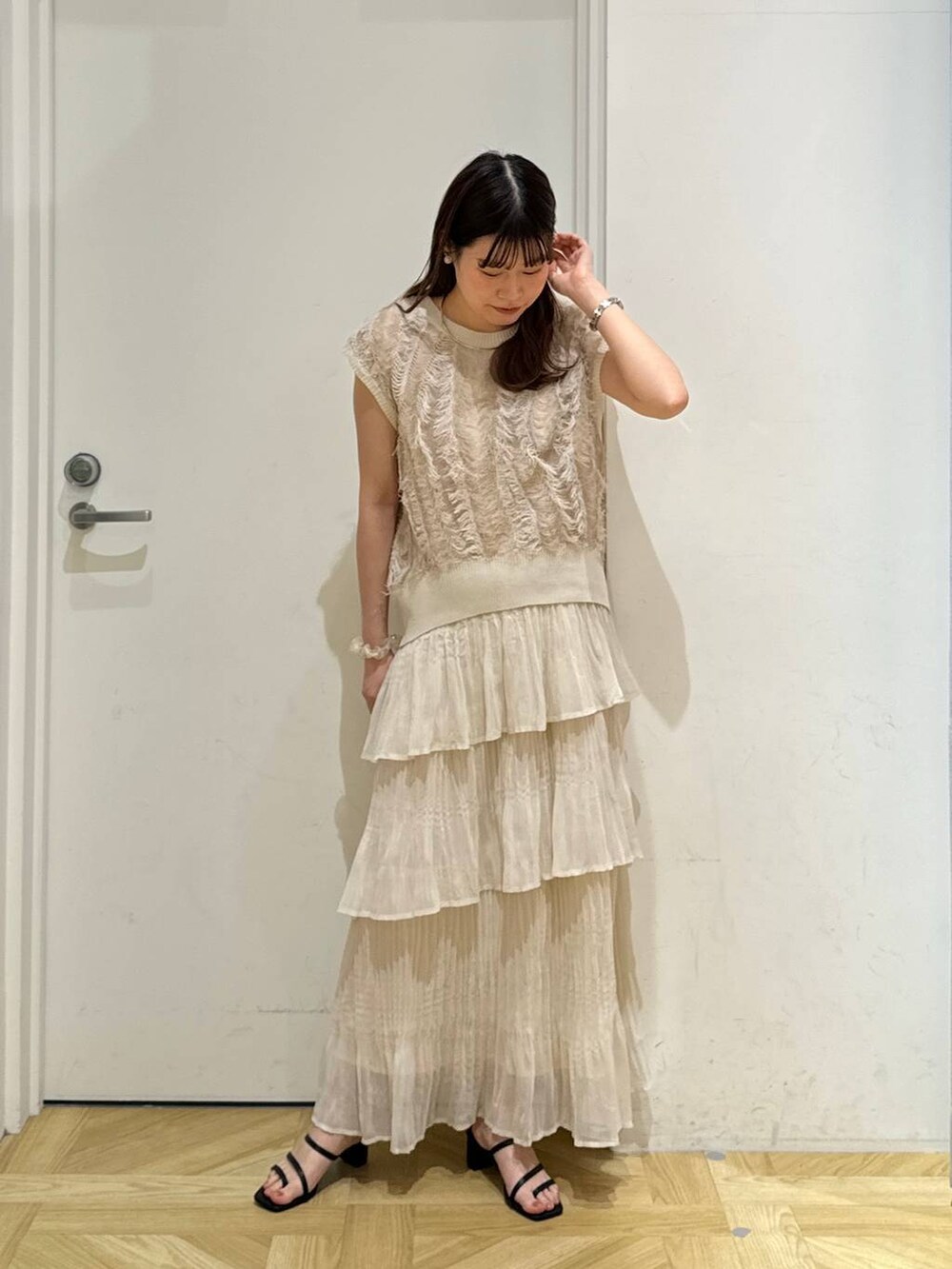 ブラック系のサンダル、ベージュ系のニット/セーター、ホワイト系のスカートを着用したレディースの夏コーディネートの2枚目の写真