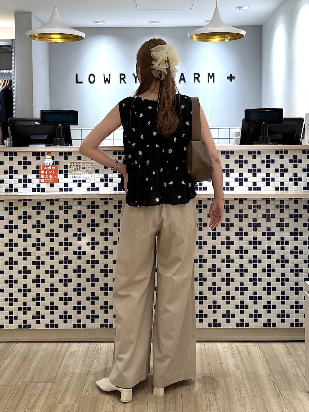 ベージュ系のデニムパンツ、ブラウン系のショルダーバッグ、ホワイト系のサンダルを着用したレディースの夏コーディネートの6枚目の写真