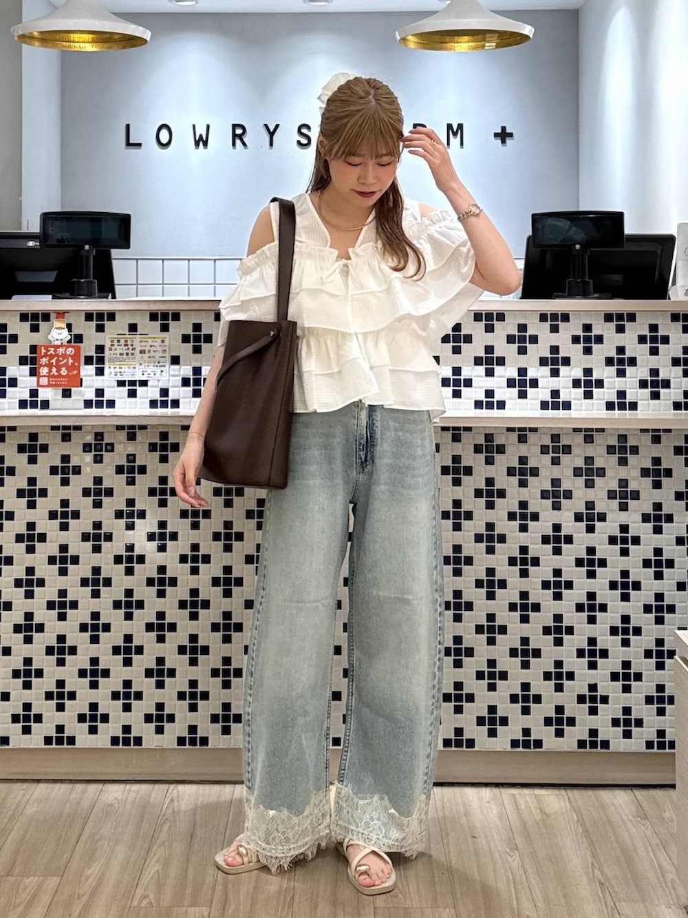 ブルー系のデニムパンツ、ホワイト系のサンダル、ブラウン系のトートバッグを着用したレディースの夏コーディネートの5枚目の写真