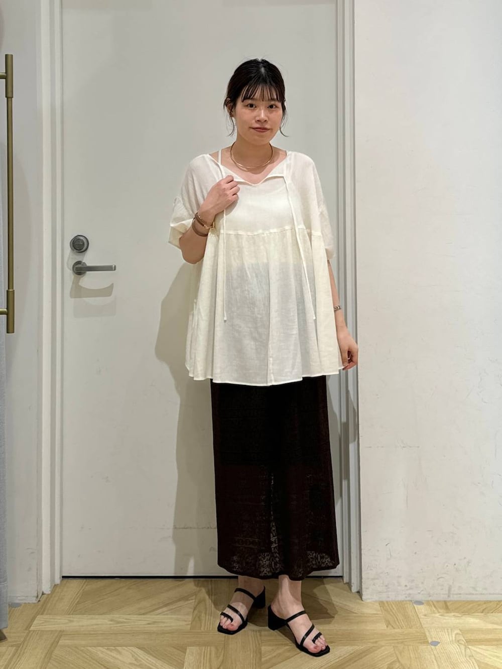 ブラック系のサンダル、ブラウン系のスカート、ホワイト系のシャツ/ブラウスを着用したレディースの夏コーディネートの2枚目の写真