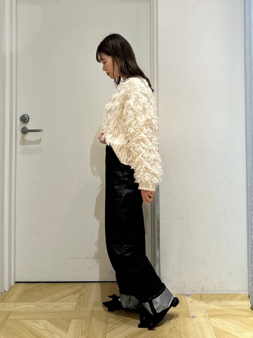 ブラック系のパンプス、グレー系のデニムパンツ、ホワイト系のカーディガン/ボレロを着用したレディースの冬コーディネートの2枚目の写真