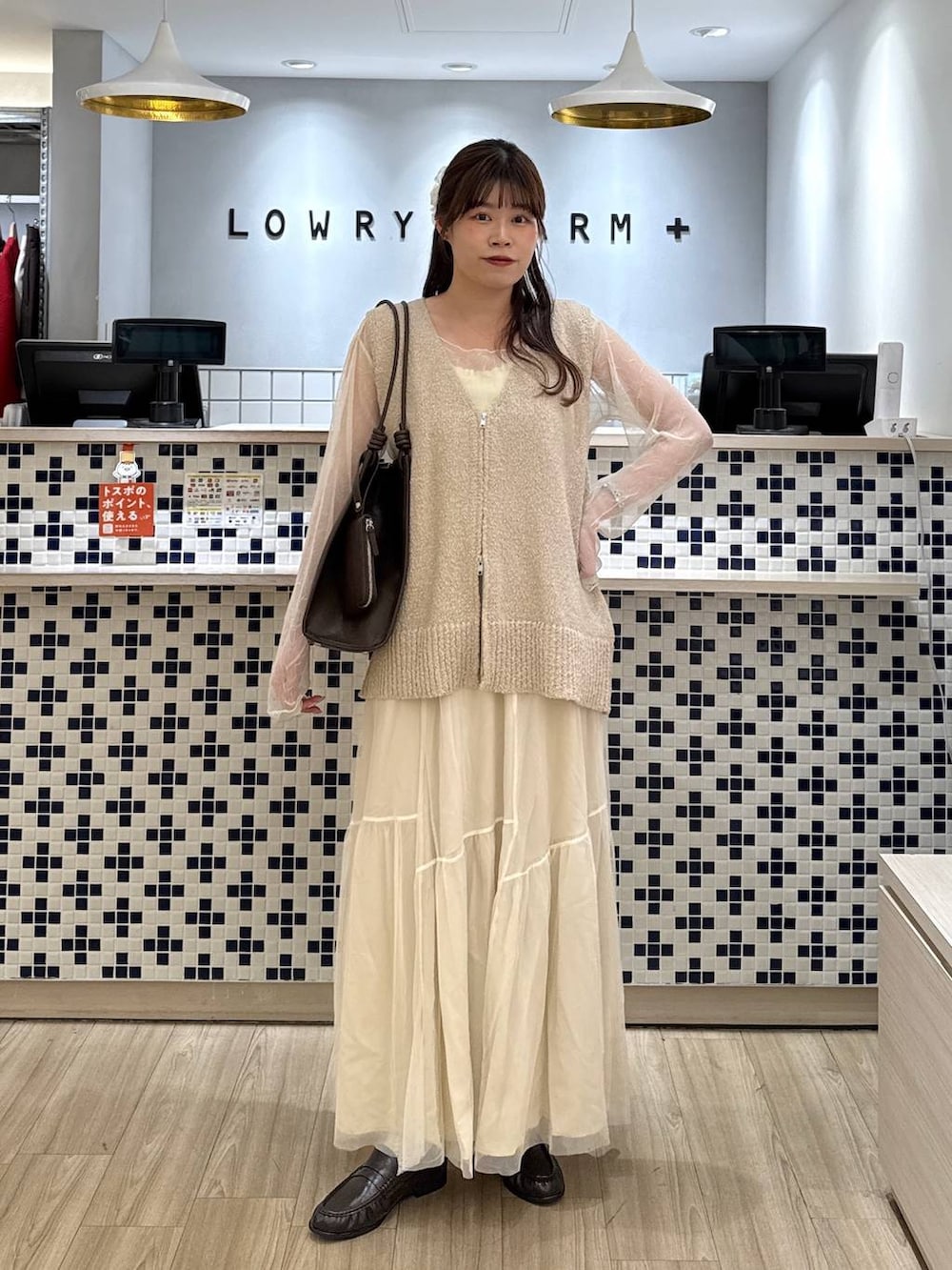 ブラウン系のローファー、ブラウン系のトートバッグ、ホワイト系のスカートを着用したレディースの春コーディネートの2枚目の写真