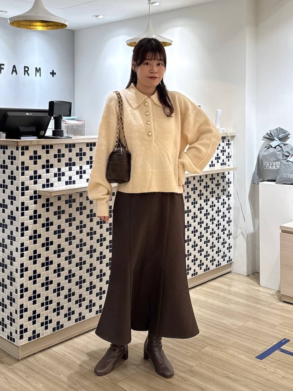 ブラウン系のスカート、ブラウン系のブーツ、ホワイト系のニット/セーターを着用したレディースの冬コーディネートの2枚目の写真