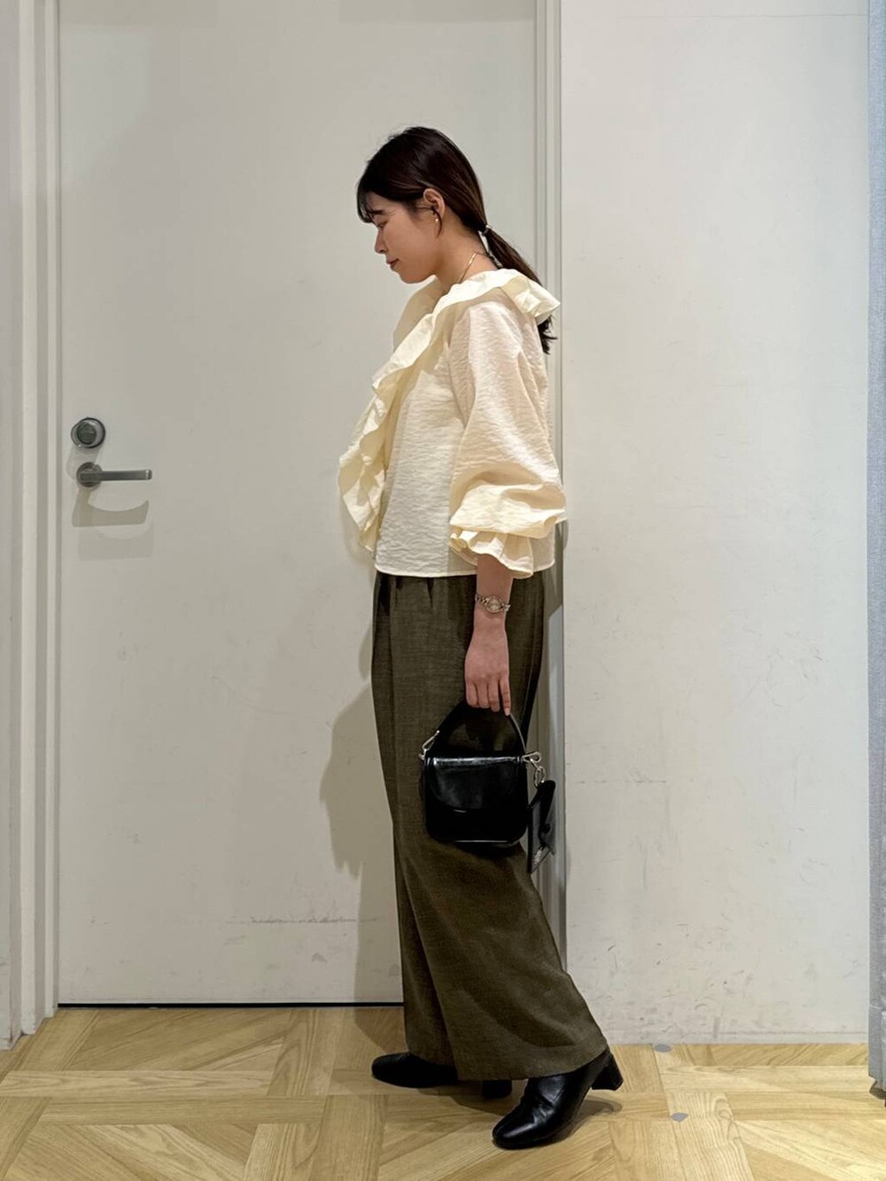 ブラック系のブーツ、ブラウン系のスラックス、ホワイト系のキャミソールを着用したレディースの春コーディネートの5枚目の写真