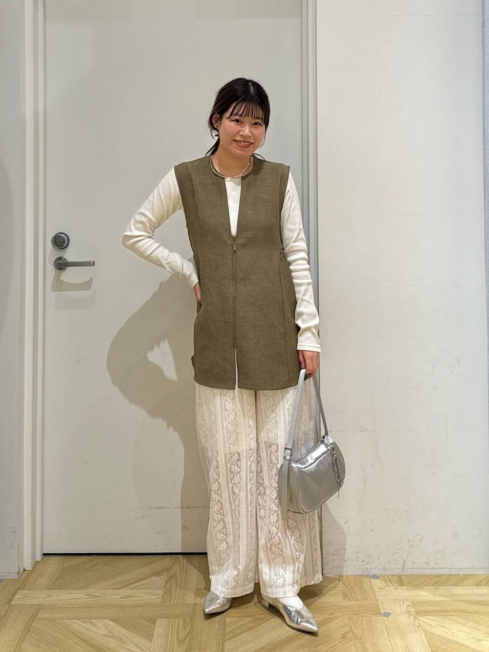 ブラウン系のベスト、ホワイト系のTシャツ/カットソー、シルバー系のトートバッグを着用したレディースの春コーディネートの2枚目の写真