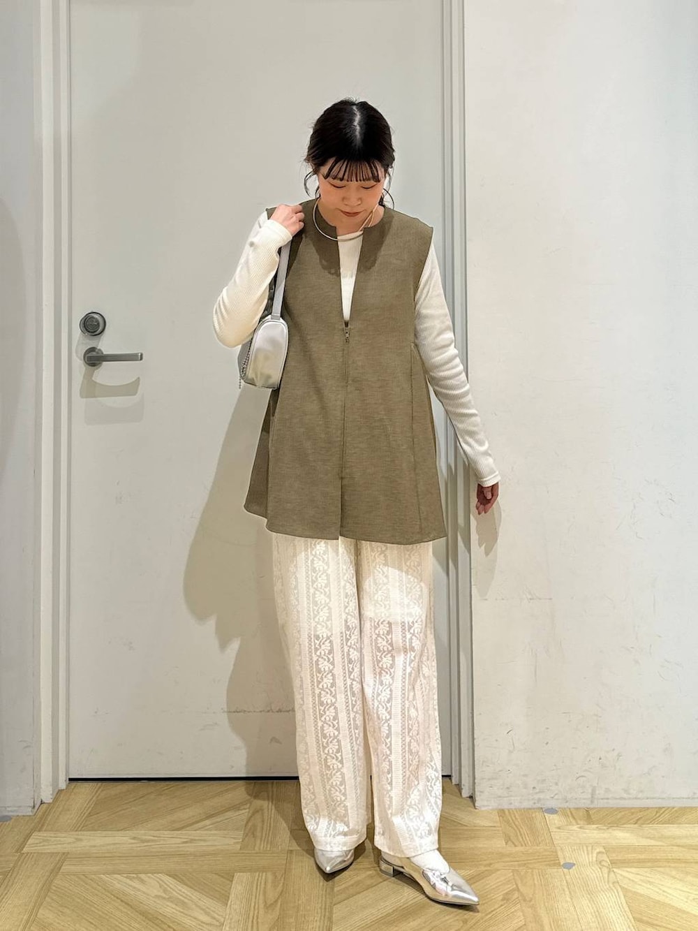 ブラウン系のベスト、ホワイト系のTシャツ/カットソー、シルバー系のトートバッグを着用したレディースの春コーディネートの3枚目の写真