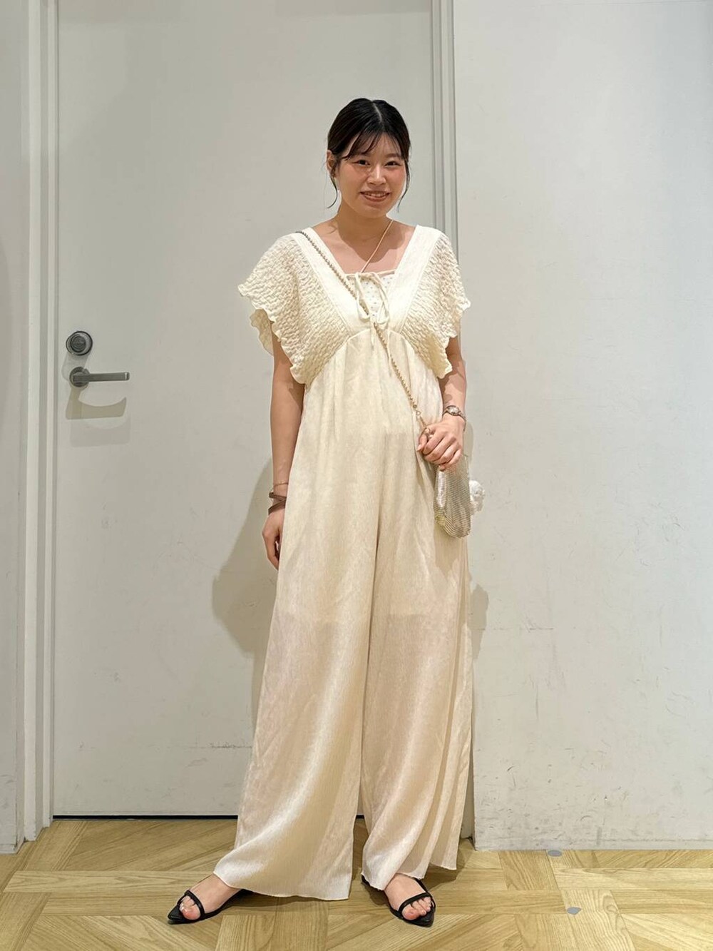 ゴールド系のショルダーバッグ、ブラック系のサンダル、ホワイト系のサロペット/オーバーオールを着用したレディースの夏コーディネートの2枚目の写真