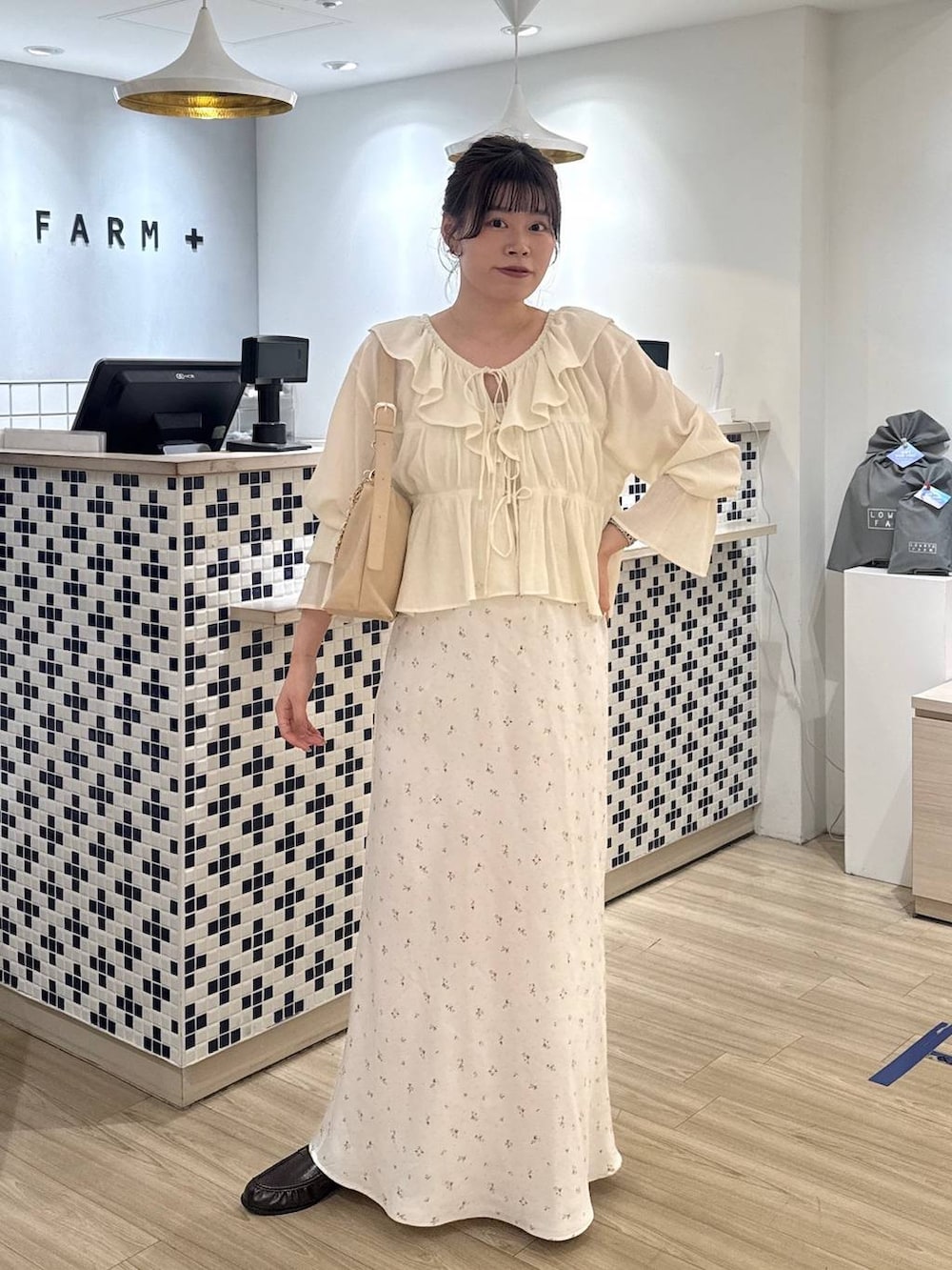 ホワイト系のスカート、ベージュ系のショルダーバッグ、ブラウン系のローファーを着用したレディースの春コーディネートの3枚目の写真