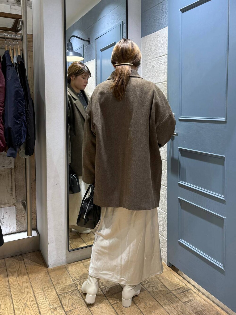 ブラウン系のチェスターコート、ホワイト系のブーツ、ブラック系のボストンバッグを着用したレディースの秋コーディネートの4枚目の写真