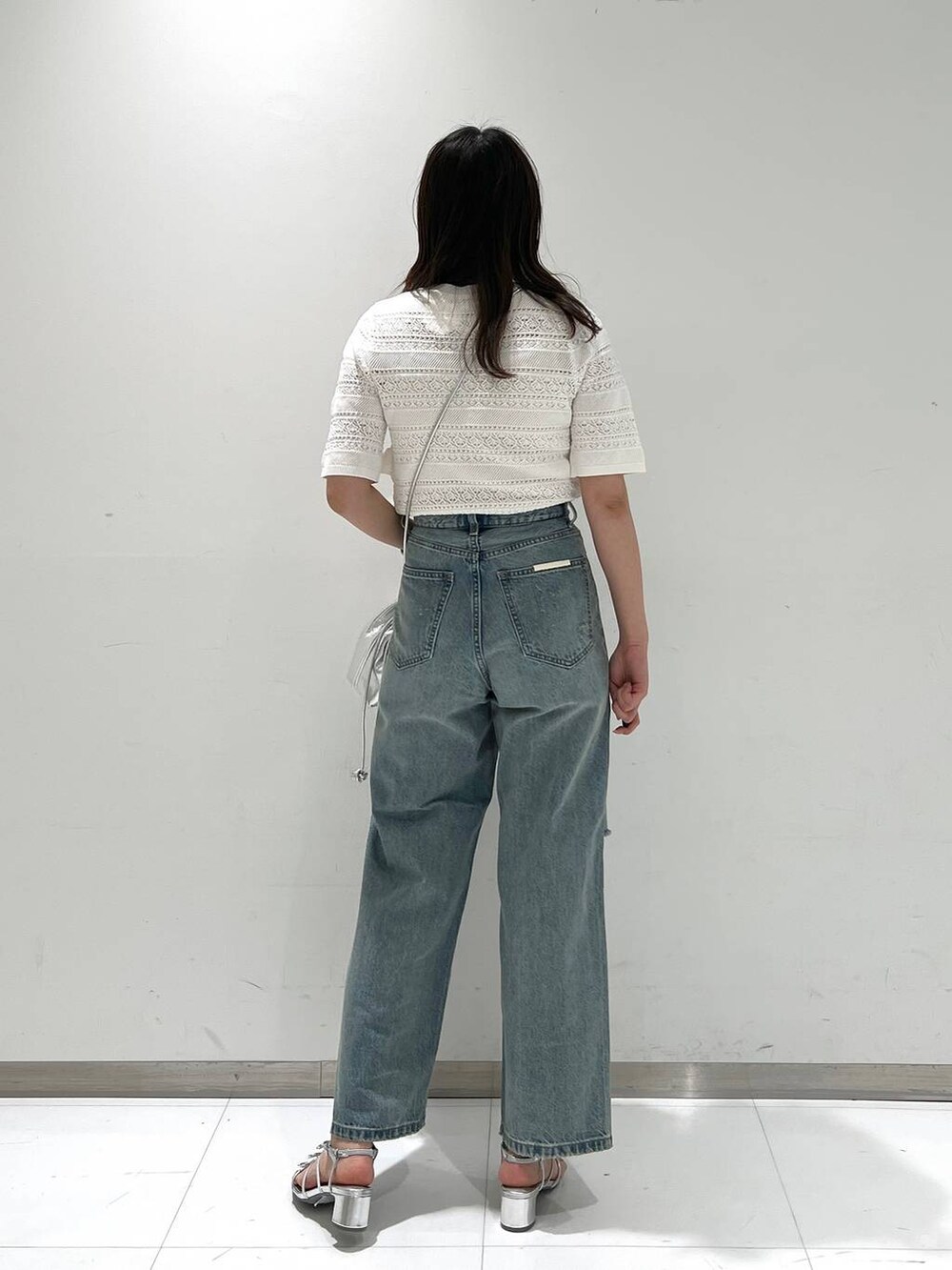 シルバー系のサンダル、シルバー系のショルダーバッグ、ブルー系のデニムパンツを着用したレディースの春コーディネートの3枚目の写真