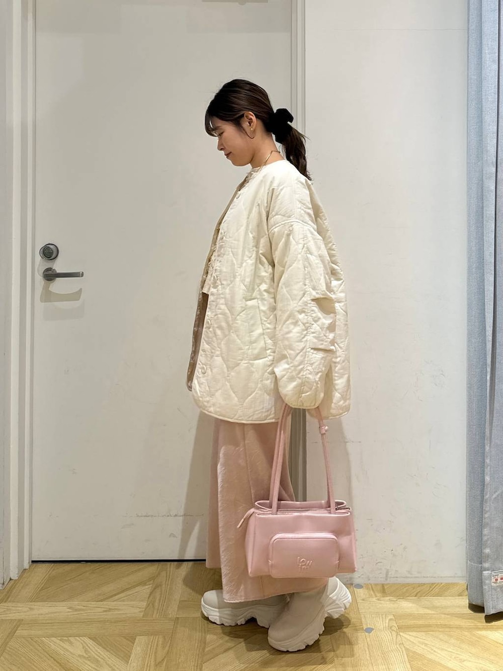 ホワイト系のブルゾン、ピンク系のショルダーバッグ、ホワイト系のブーツを着用したレディースの冬コーディネートの3枚目の写真