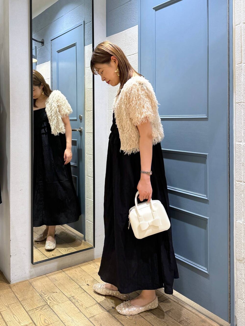 ホワイト系のボストンバッグ、ホワイト系のバレエシューズ、ブラック系のワンピースを着用したレディースの夏コーディネートの2枚目の写真