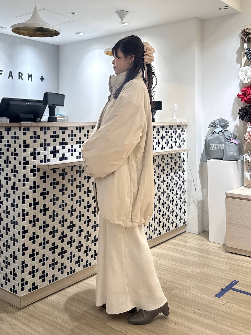 ホワイト系のスカート、ベージュ系のカーディガン/ボレロ、ブラウン系のブーツを着用したレディースの冬コーディネートの3枚目の写真