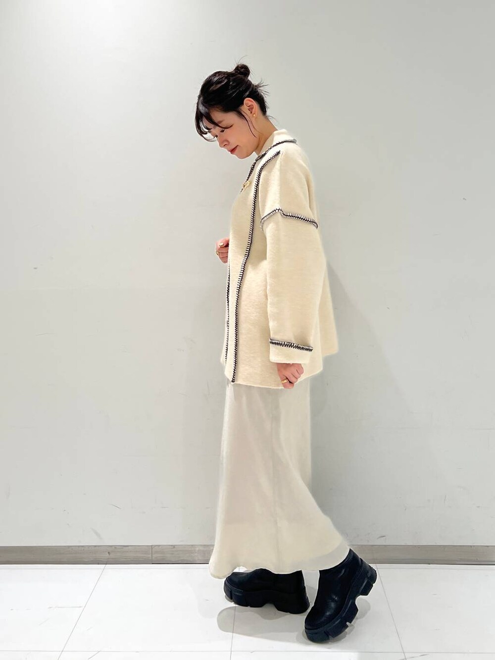 ブラック系のブーツ、ホワイト系のスカート、ホワイト系のカーディガン/ボレロを着用したレディースの秋コーディネートの3枚目の写真