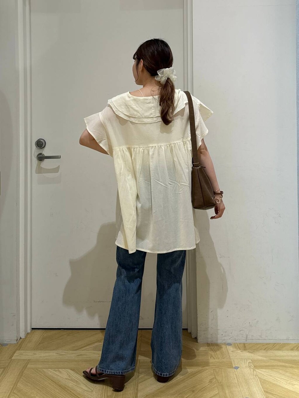 ブラウン系のショルダーバッグ、ブラック系のサンダル、ホワイト系のシャツ/ブラウスを着用したレディースの夏コーディネートの5枚目の写真