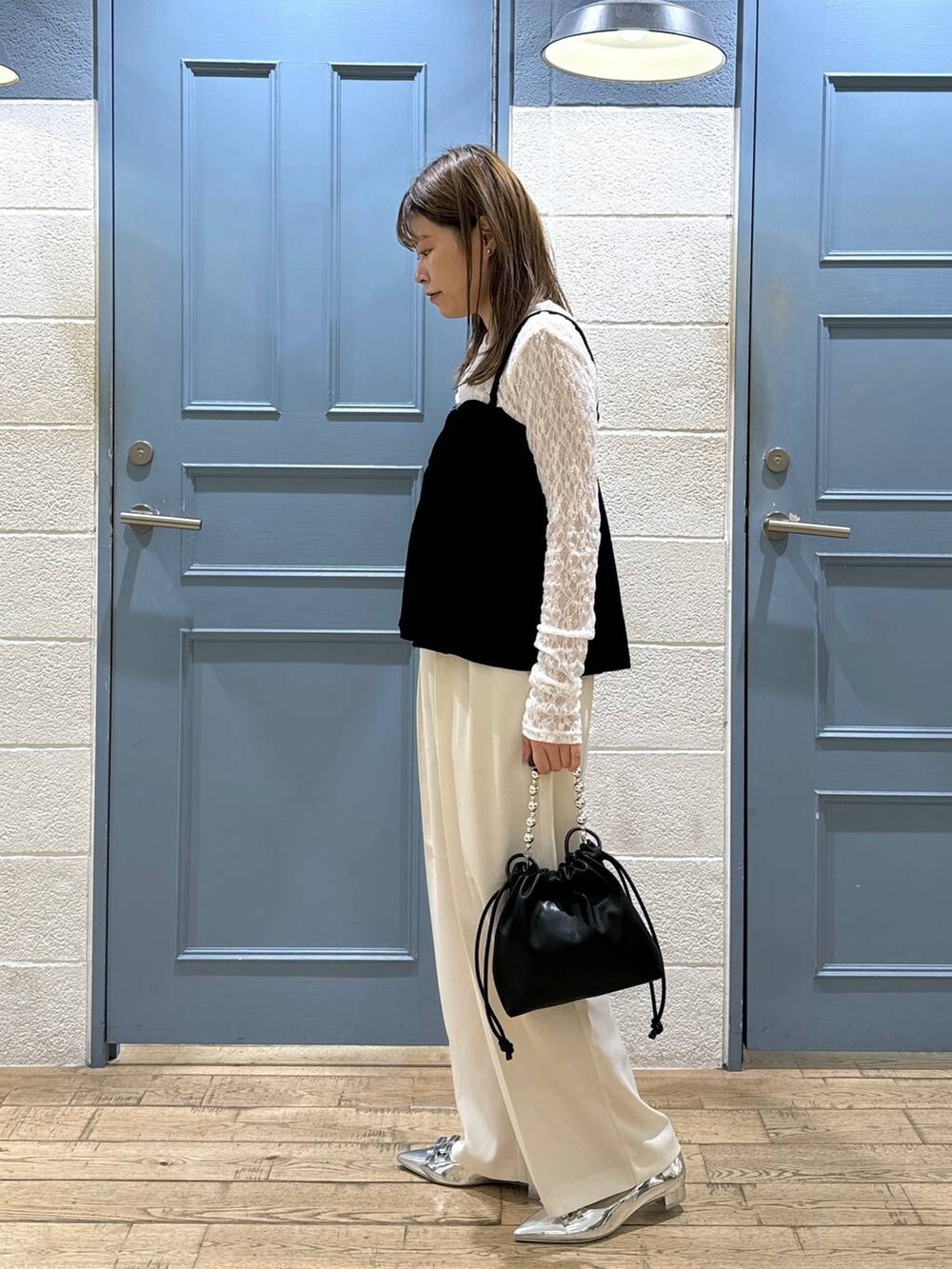 ホワイト系のスラックス、シルバー系のパンプス、ブラック系のショルダーバッグを着用したレディースの秋コーディネートの2枚目の写真