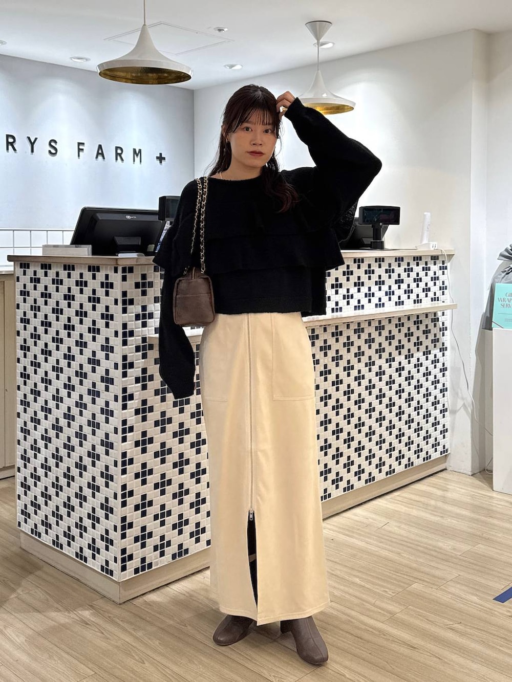 ホワイト系のスカート、ブラウン系のブーツ、ブラウン系のショルダーバッグを着用したレディースの冬コーディネートの2枚目の写真