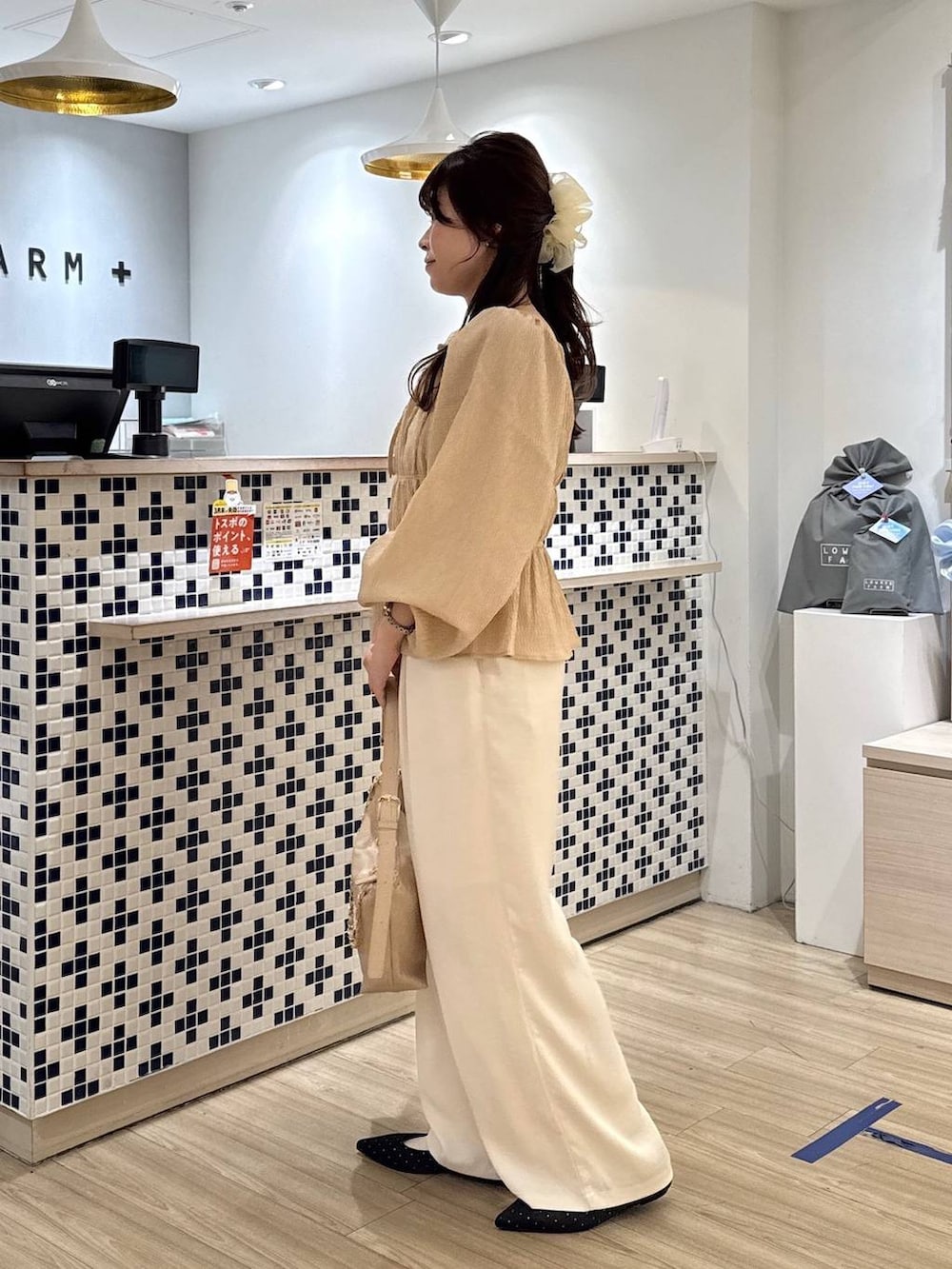 ブラック系のパンプス、ベージュ系のショルダーバッグ、ホワイト系のその他パンツを着用したレディースの春コーディネートの3枚目の写真