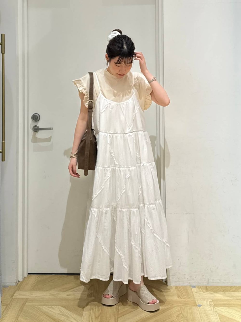 ホワイト系のサンダル、ホワイト系のワンピース、ブラウン系のショルダーバッグを着用したレディースの夏コーディネートの2枚目の写真