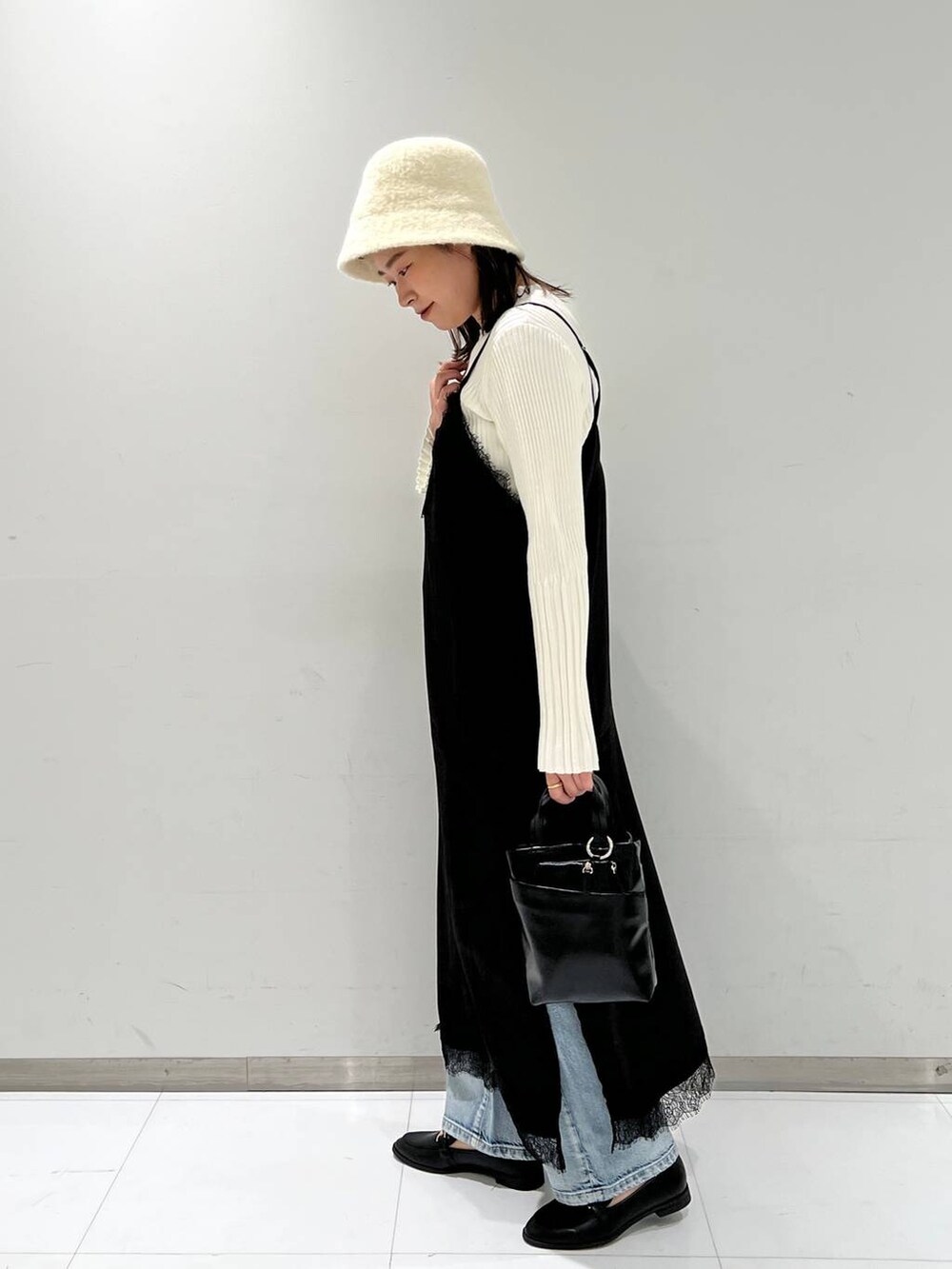 ブルー系のデニムパンツ、ブラック系のローファー、ホワイト系のニット/セーターを着用したレディースの秋コーディネートの3枚目の写真