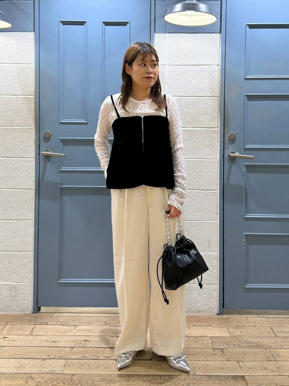 ホワイト系のスラックス、シルバー系のパンプス、ブラック系のショルダーバッグを着用したレディースの秋コーディネートの3枚目の写真