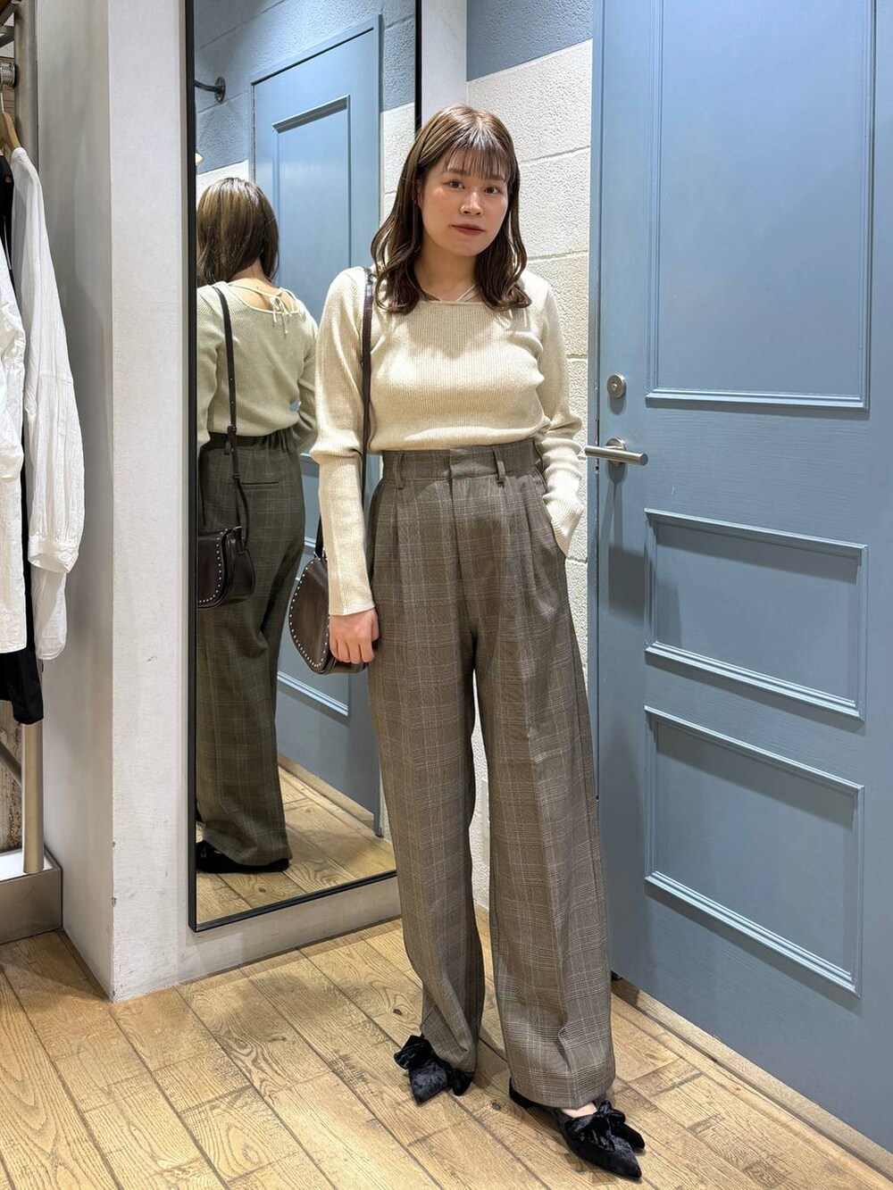 ブラック系のパンプス、ブラウン系のショルダーバッグ、ブラウン系のスラックスを着用したレディースの秋コーディネートの3枚目の写真