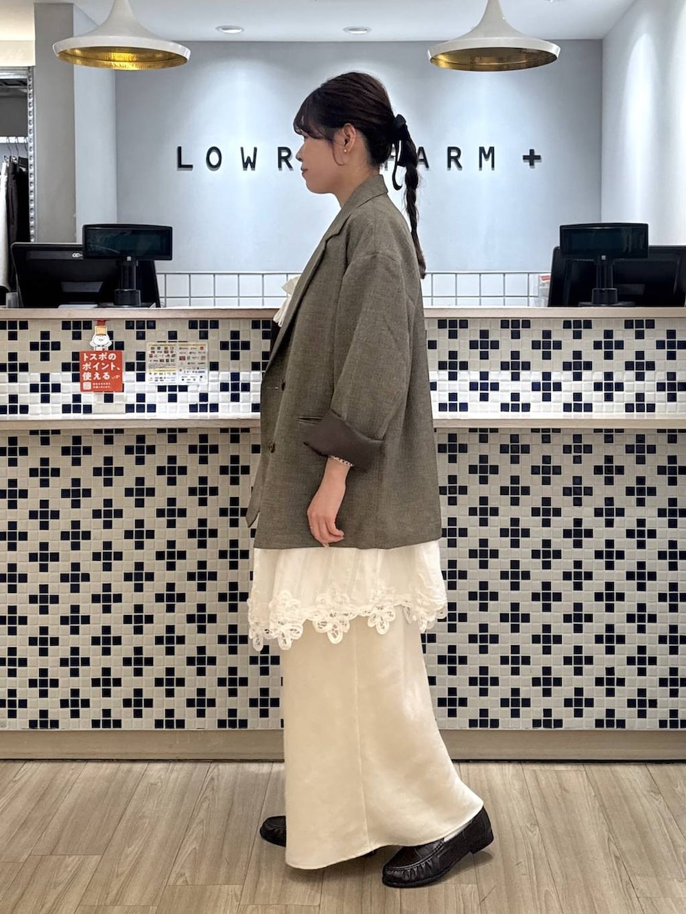 ホワイト系のスカート、ブラウン系のテーラードジャケット、ブラウン系のローファーを着用したレディースの春コーディネートの4枚目の写真