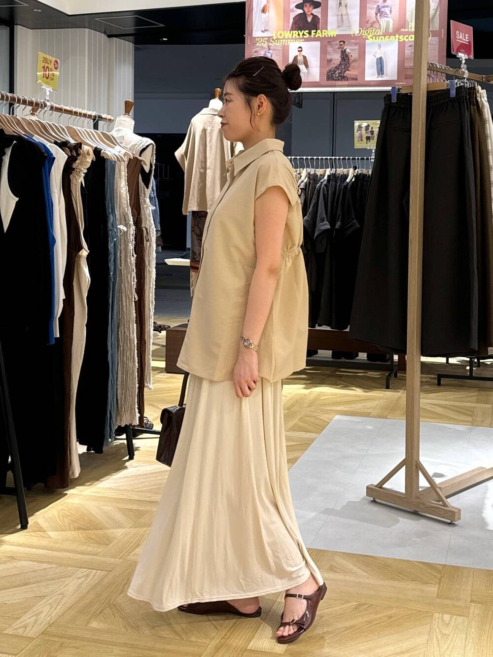 ブラウン系のサンダル、ホワイト系のスカート、ブラウン系のボストンバッグを着用したレディースの夏コーディネートの2枚目の写真