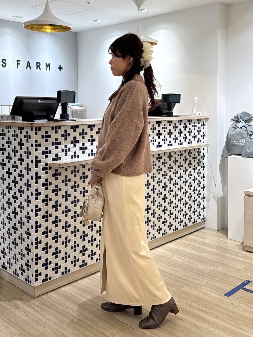 ホワイト系のスカート、ホワイト系のボストンバッグ、ブラウン系のブーツを着用したレディースの冬コーディネートの3枚目の写真